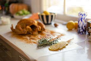 a roasted chicken on a cutting board with lemons and herbs