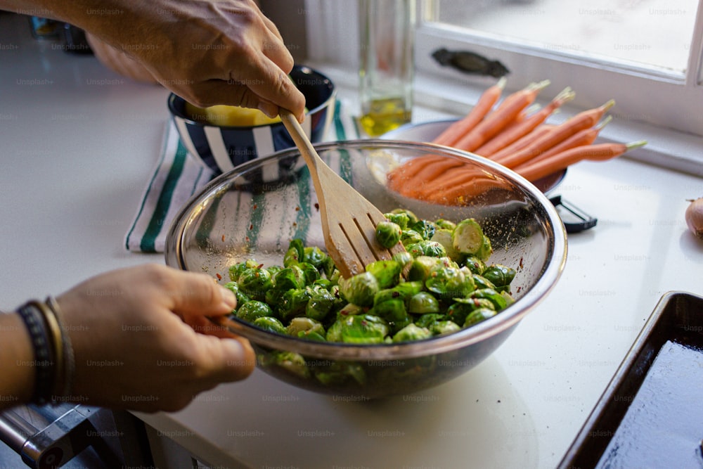 uma pessoa misturando legumes em uma tigela com uma colher de pau