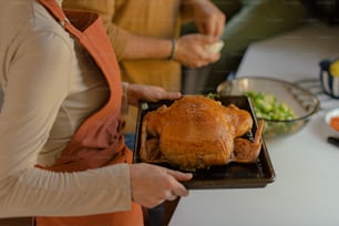 a woman holding a tray with a turkey on it
