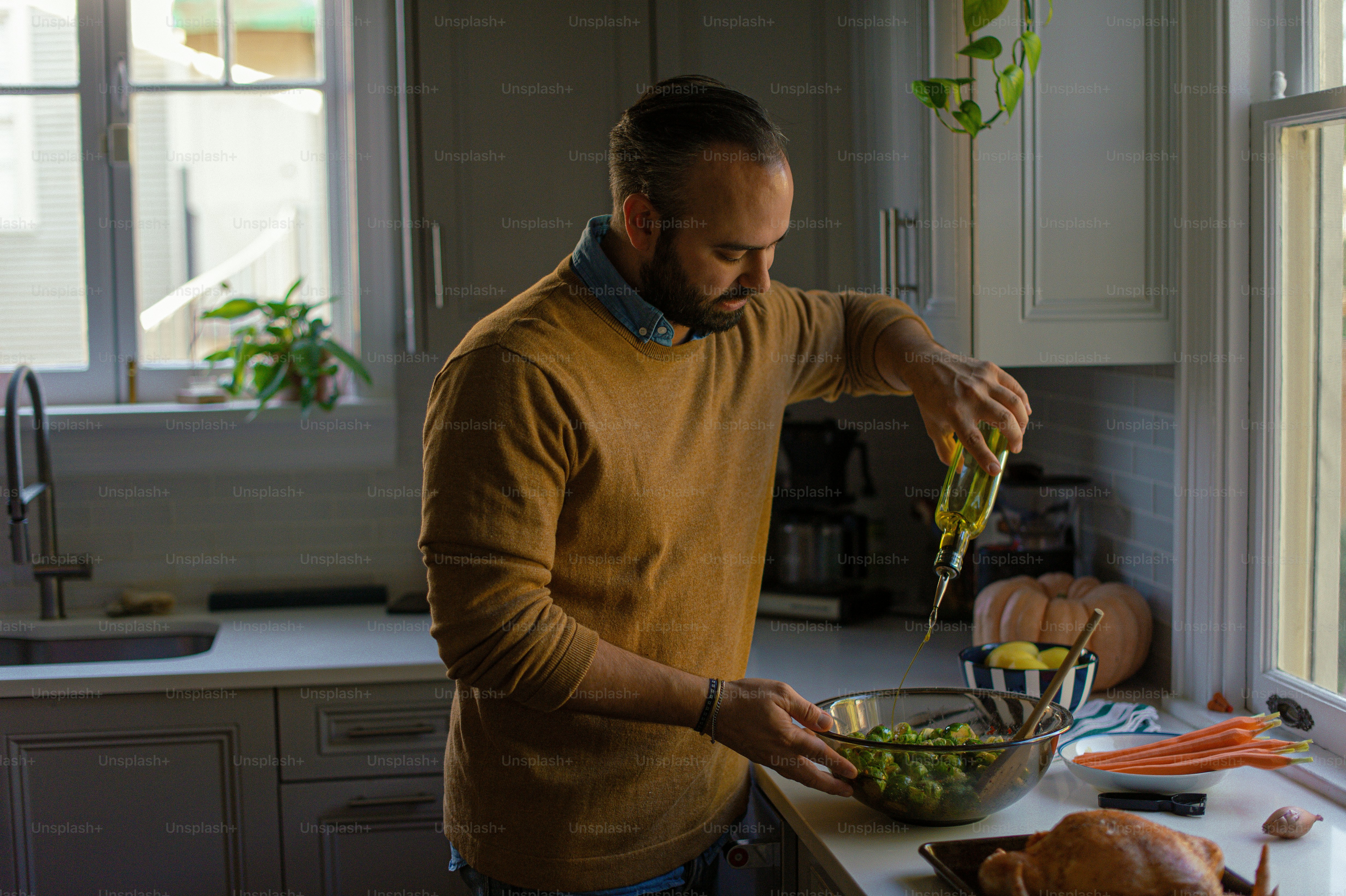 A man standing in a kitchen preparing food photo – Olive oil Image on ...