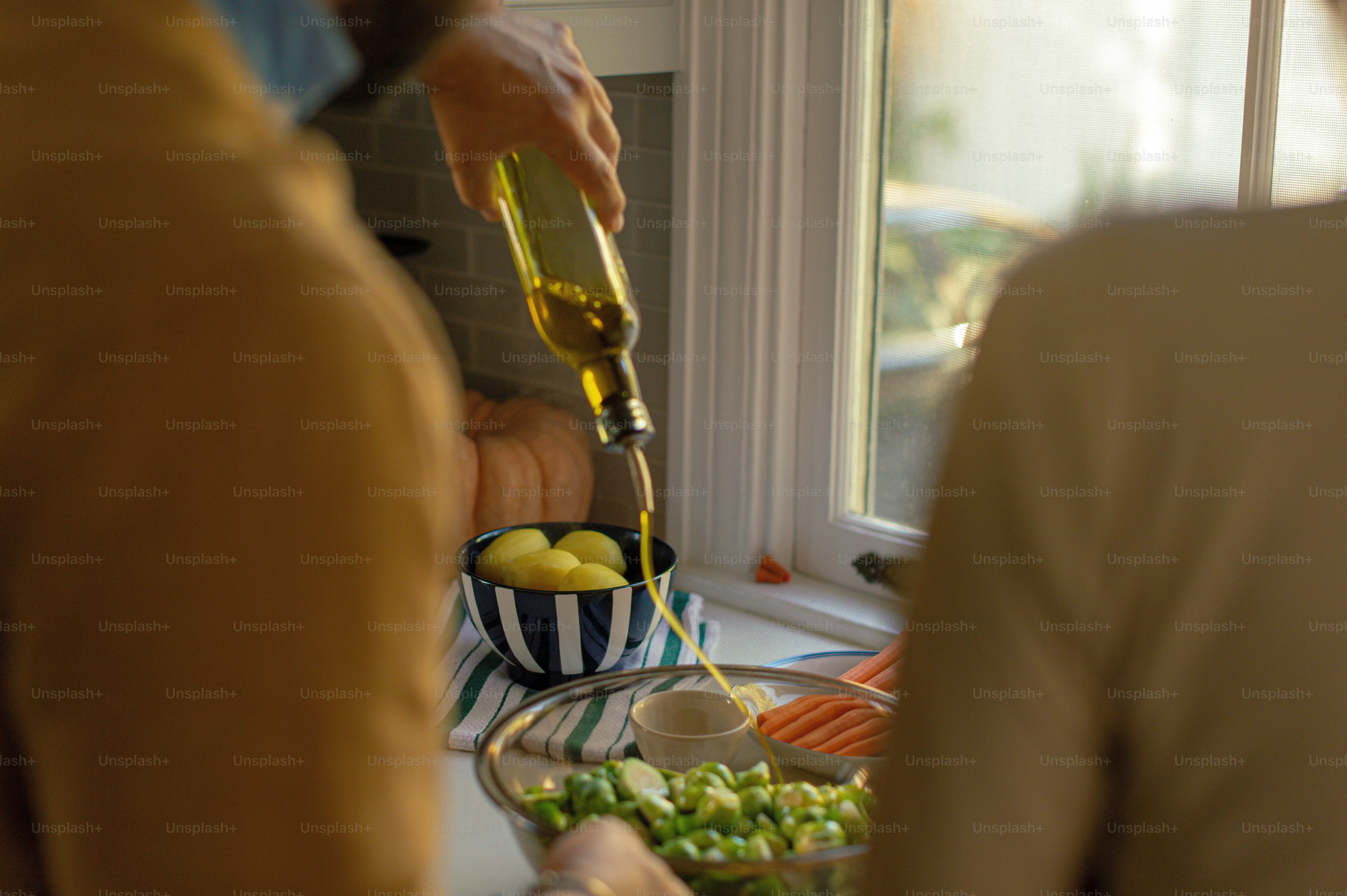 a person pouring olive oil over a bowl of vegetables