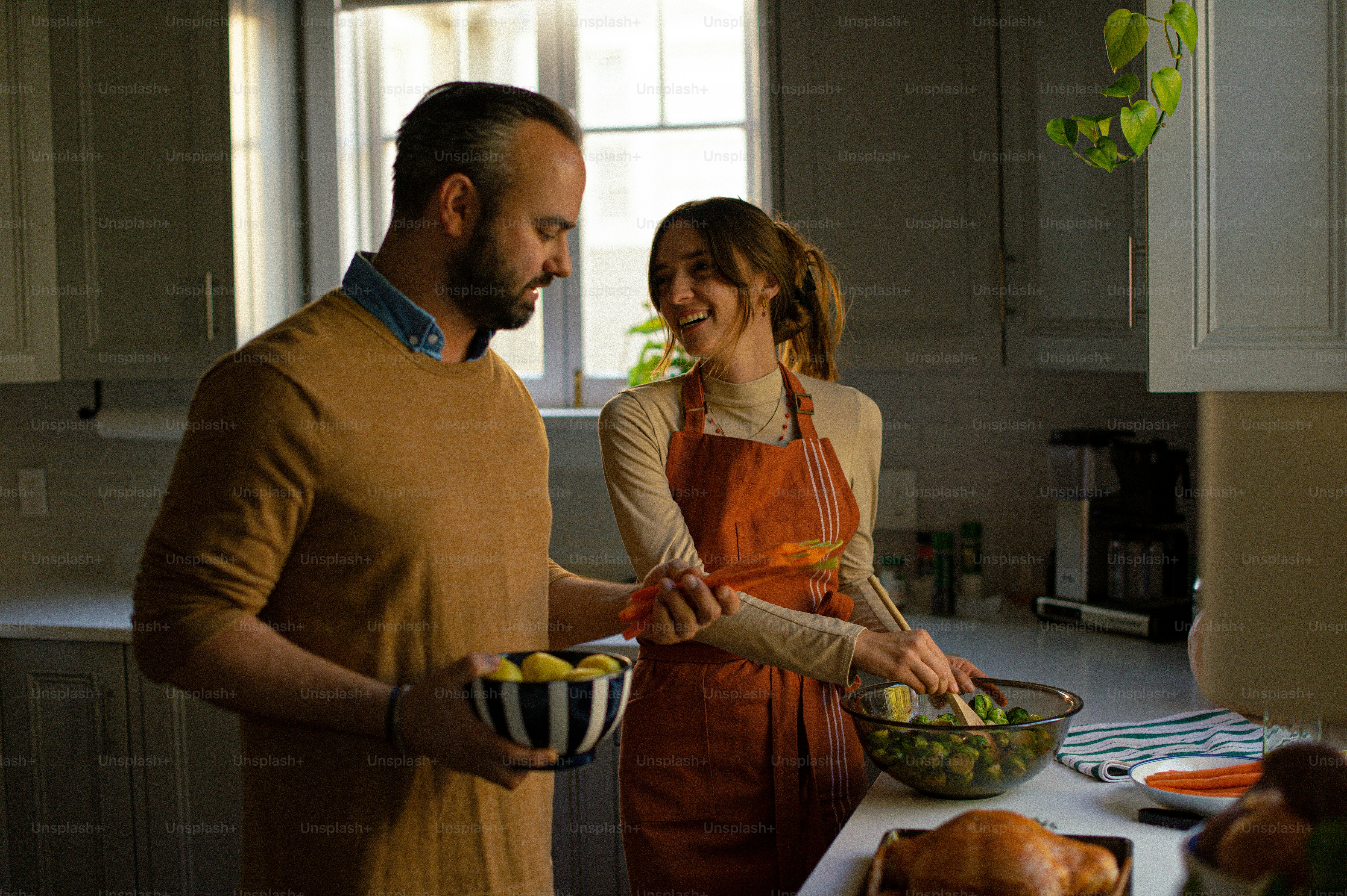 a man and a woman standing in a kitchen preparing food