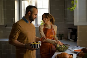 a man and a woman standing in a kitchen preparing food