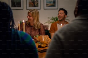 um grupo de pessoas sentadas ao redor de uma mesa com um peru sobre ela