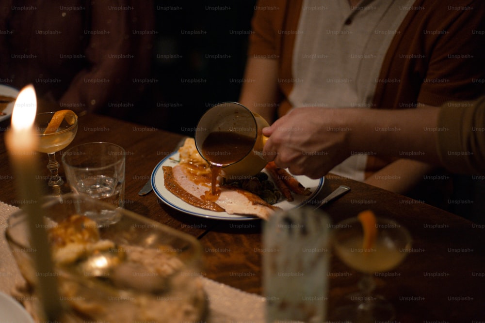 a person pouring syrup on a plate of food