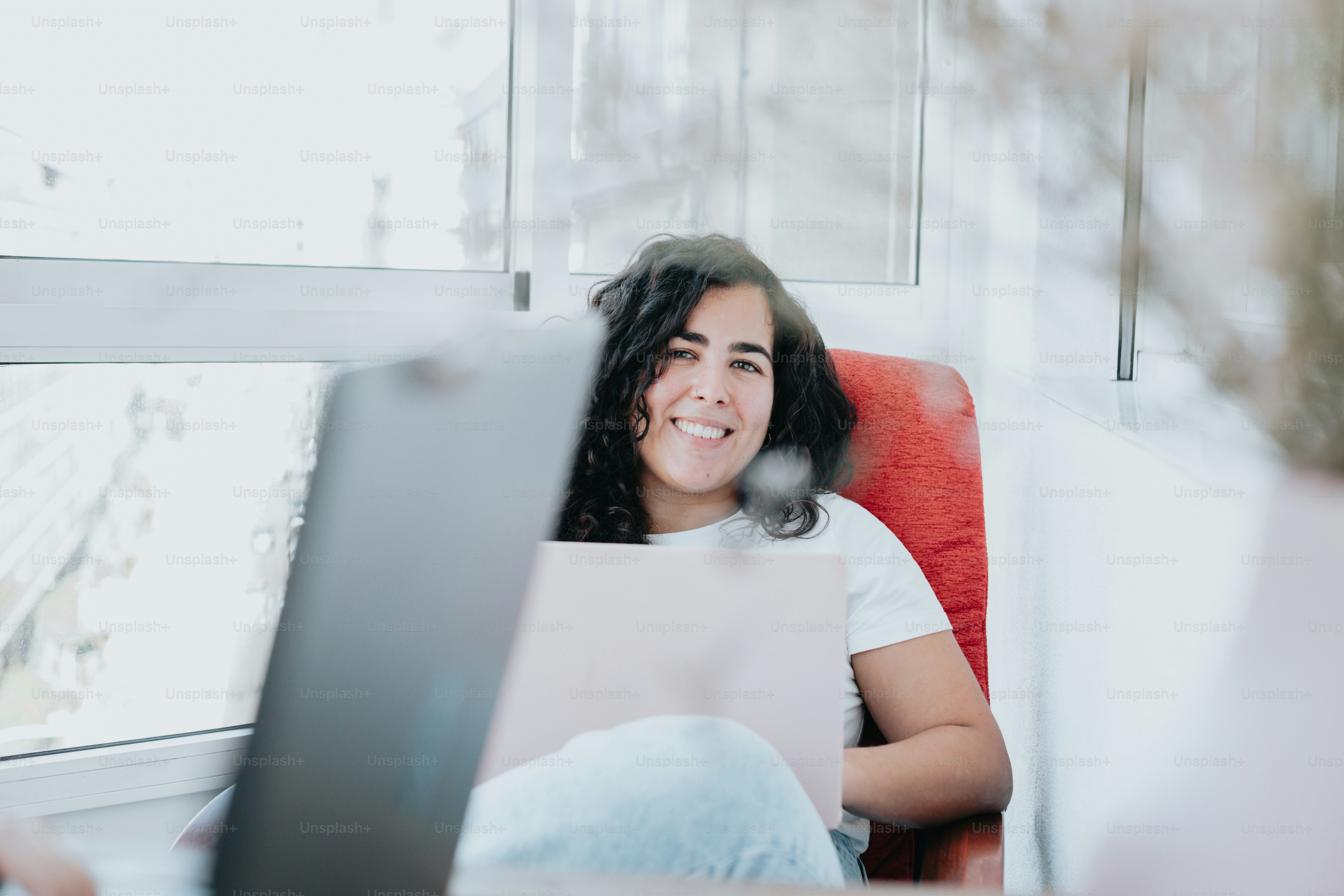 a woman sitting in a red chair with a laptop