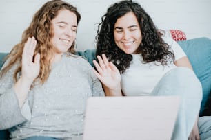 two young women sitting on a couch using a laptop