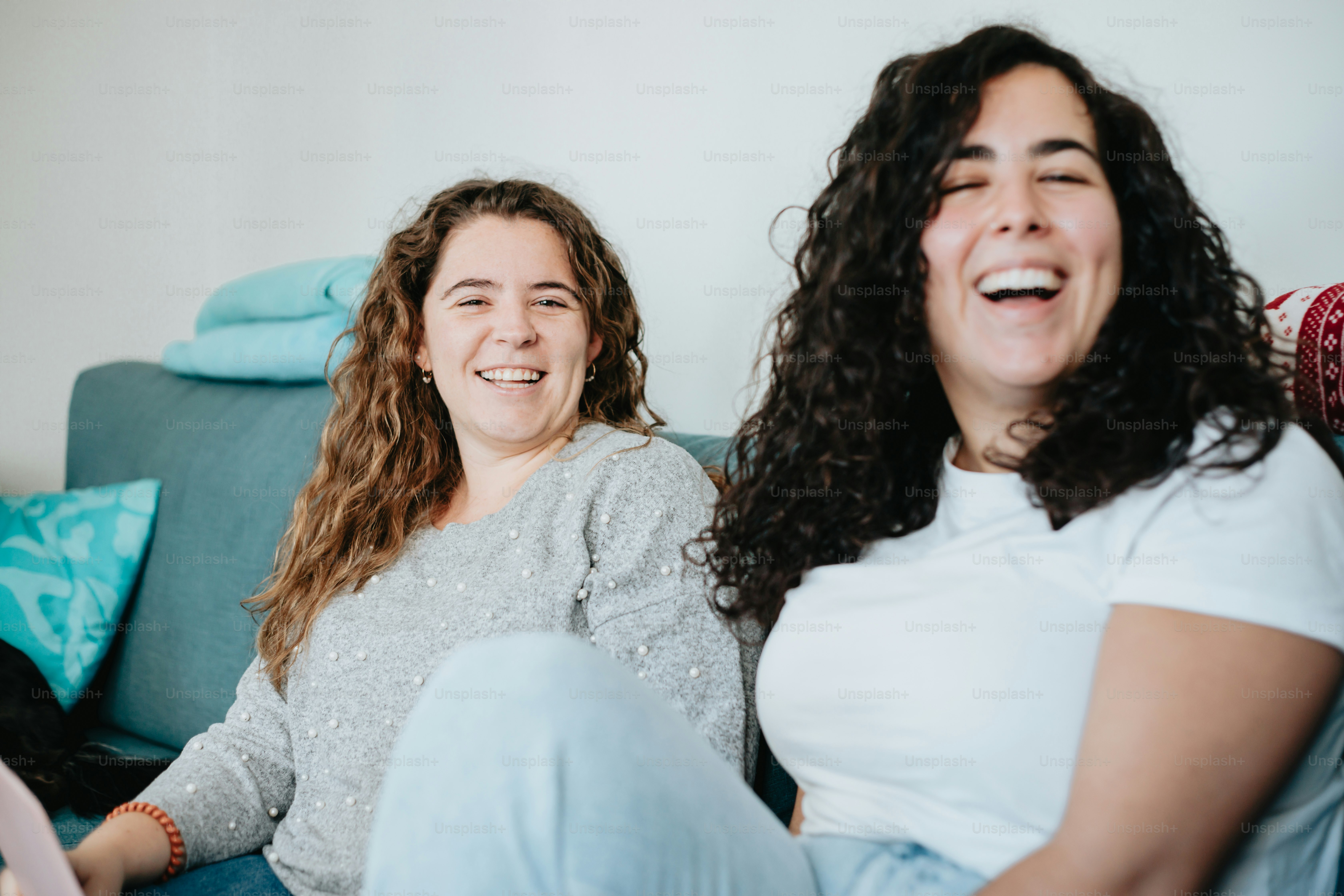 a couple of women sitting on top of a blue couch
