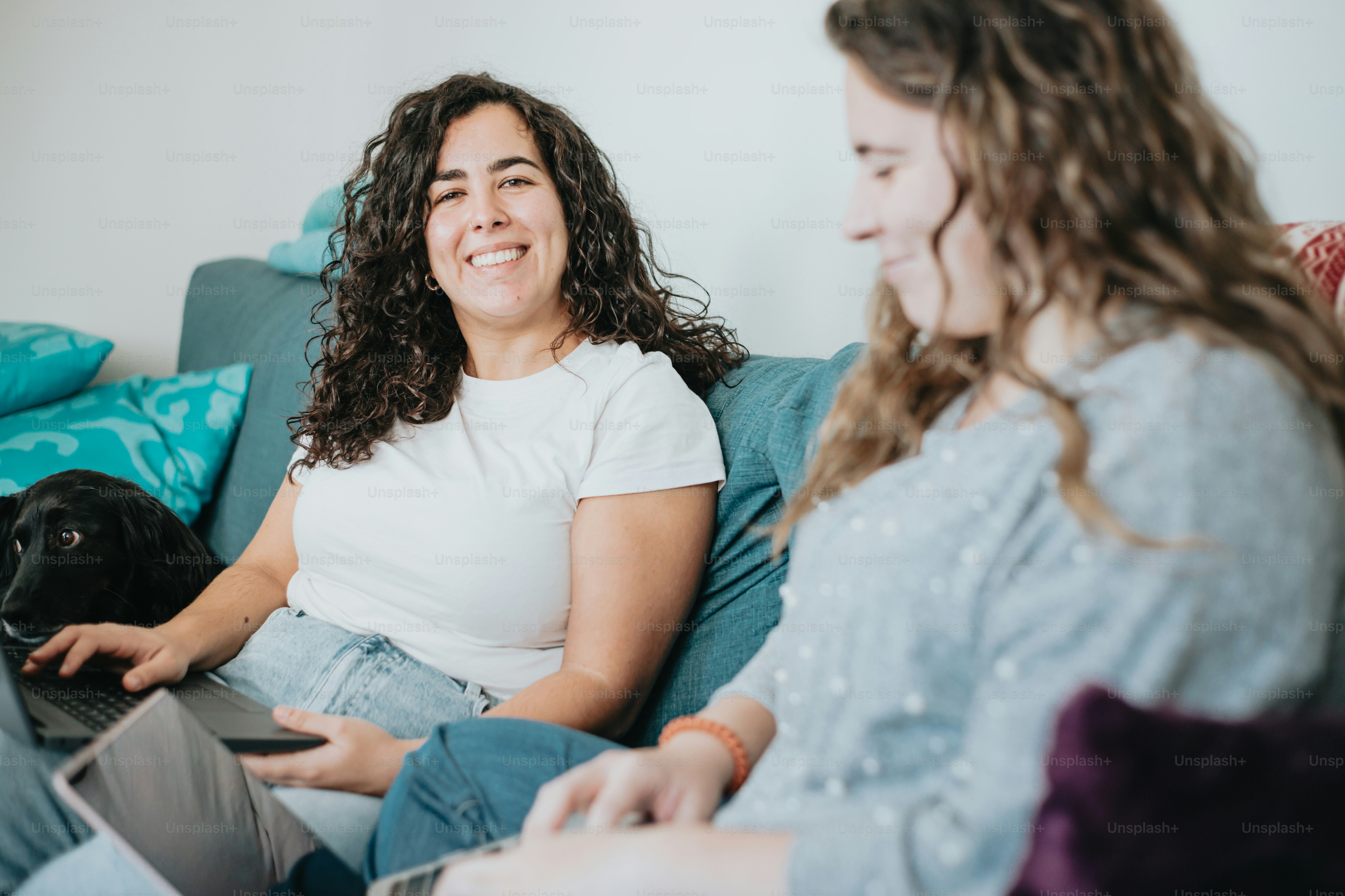 two women sitting on a couch with a dog