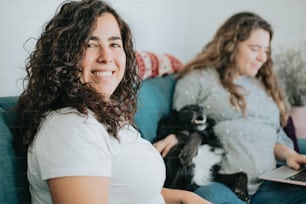 two women sitting on a couch with a dog