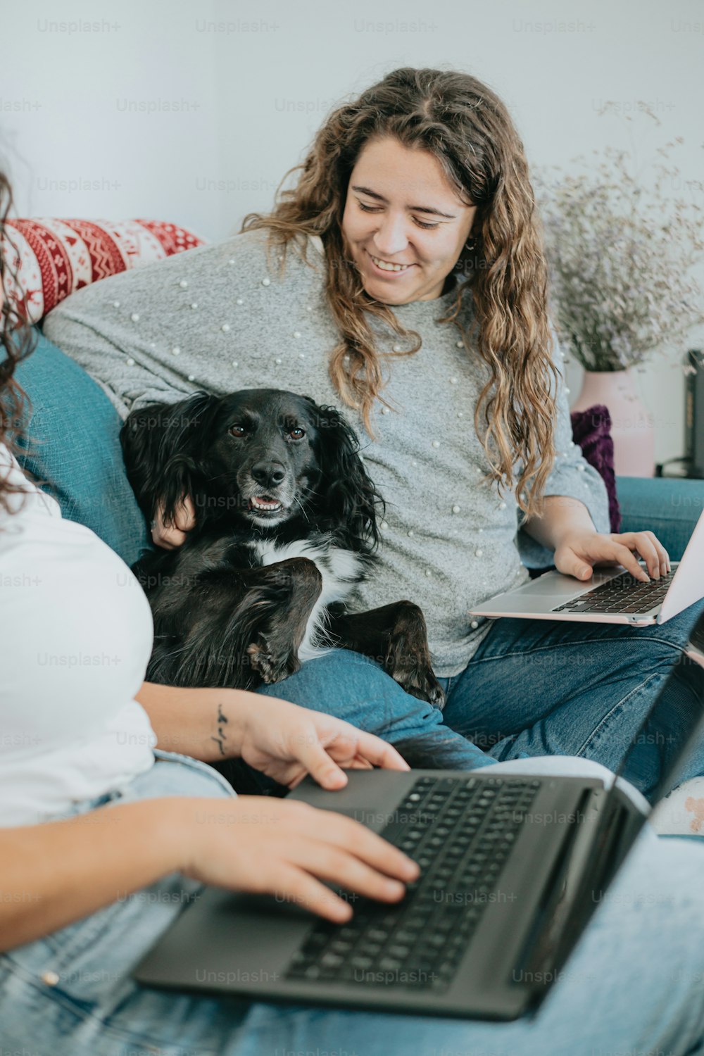 uma mulher sentada em um sofá com um cachorro e um laptop