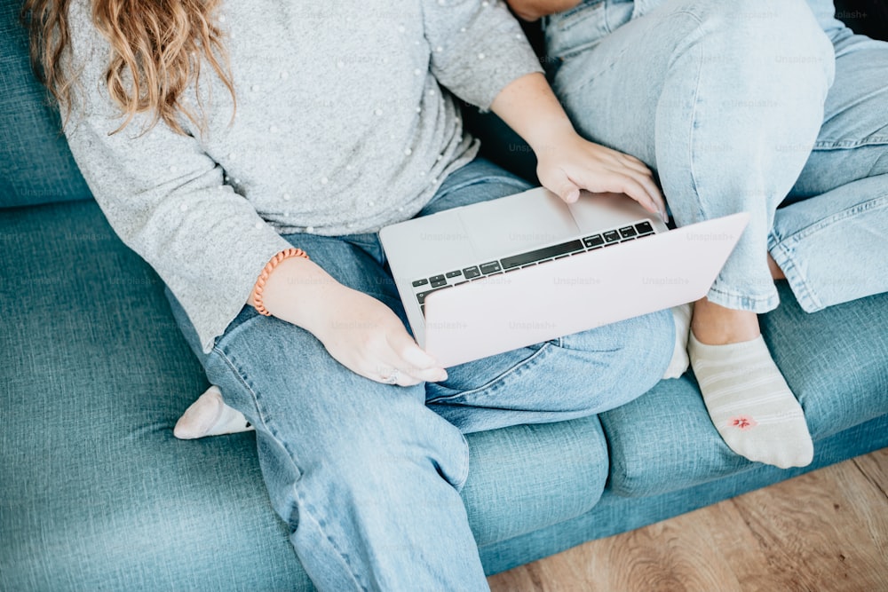 a woman sitting on a couch using a laptop computer