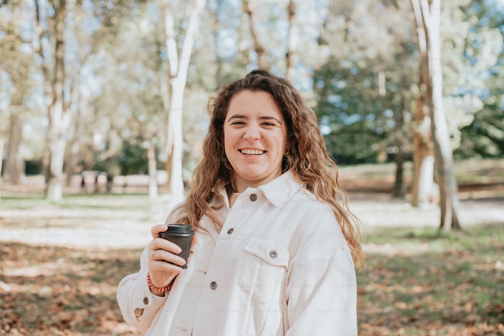 a woman holding a cup of coffee in a park