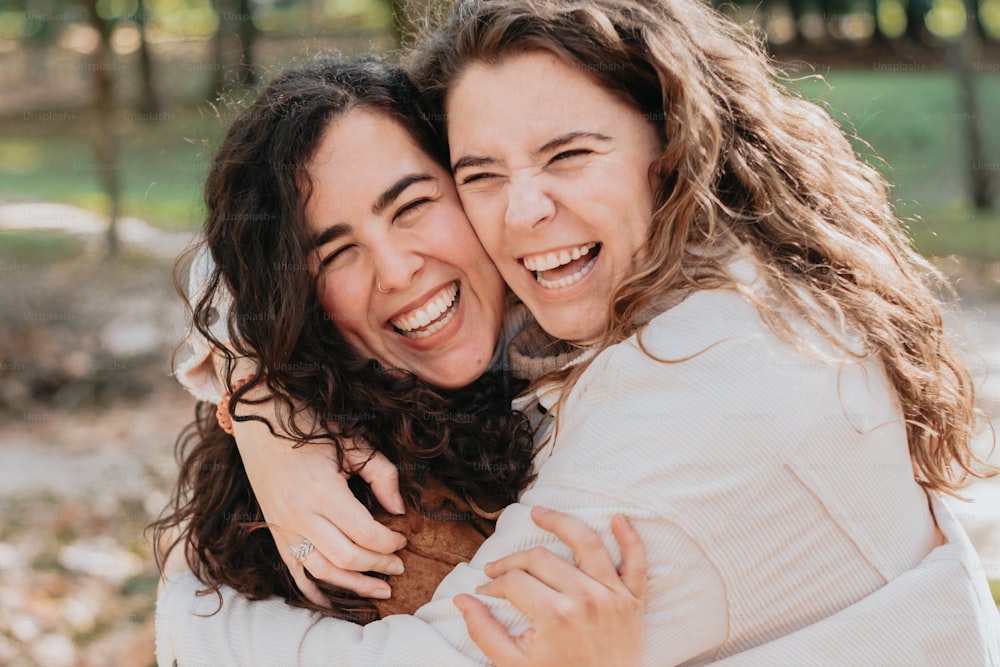 two women hugging each other in a park