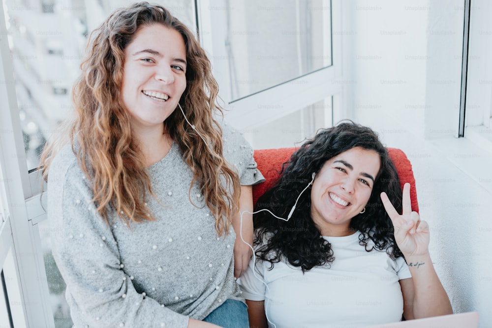 two women sitting next to each other in front of a window