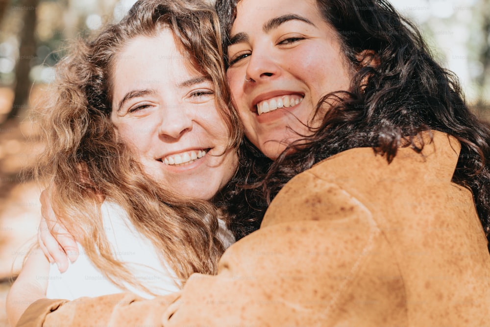 two women hugging each other in the woods