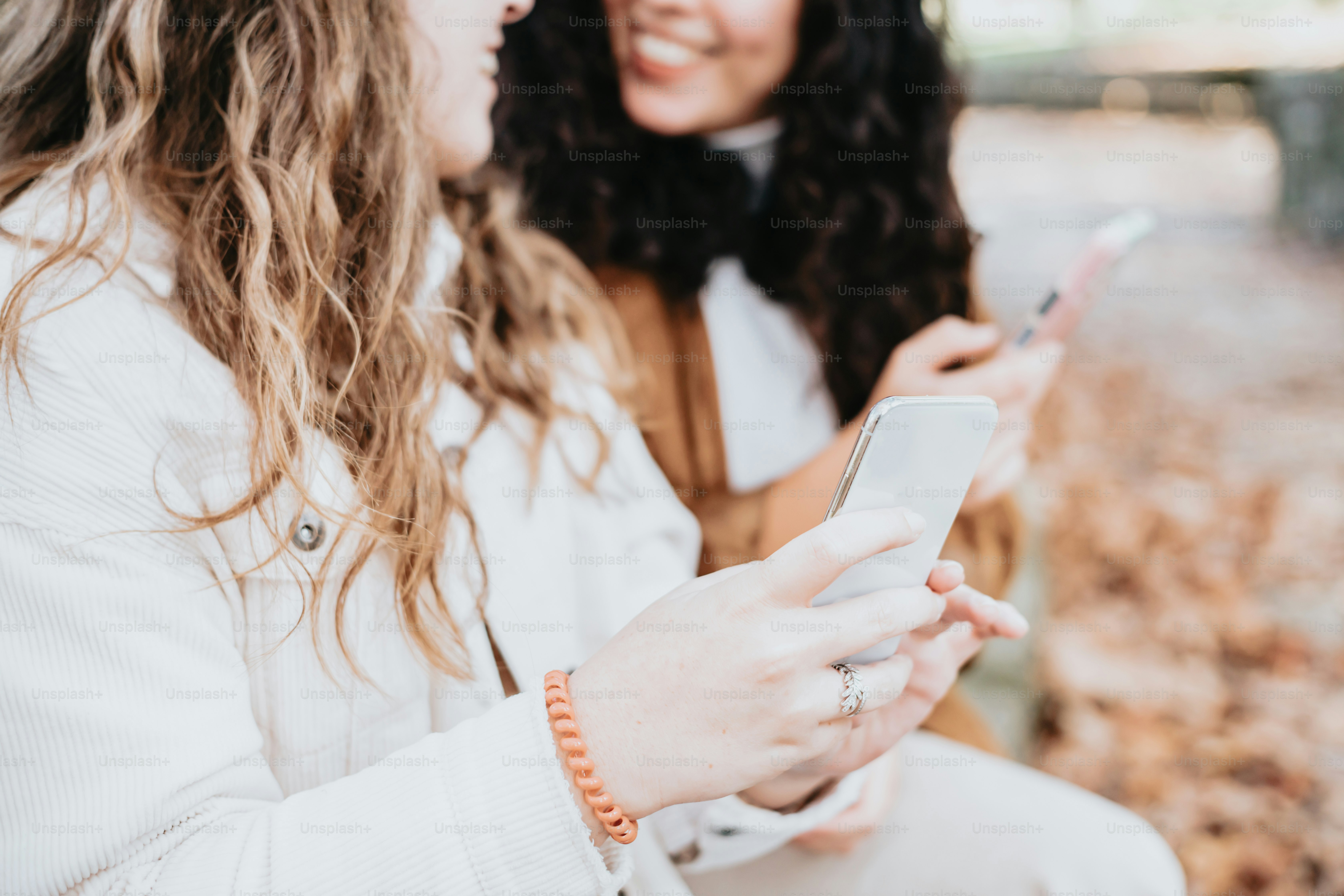 two women sitting next to each other looking at a cell phone