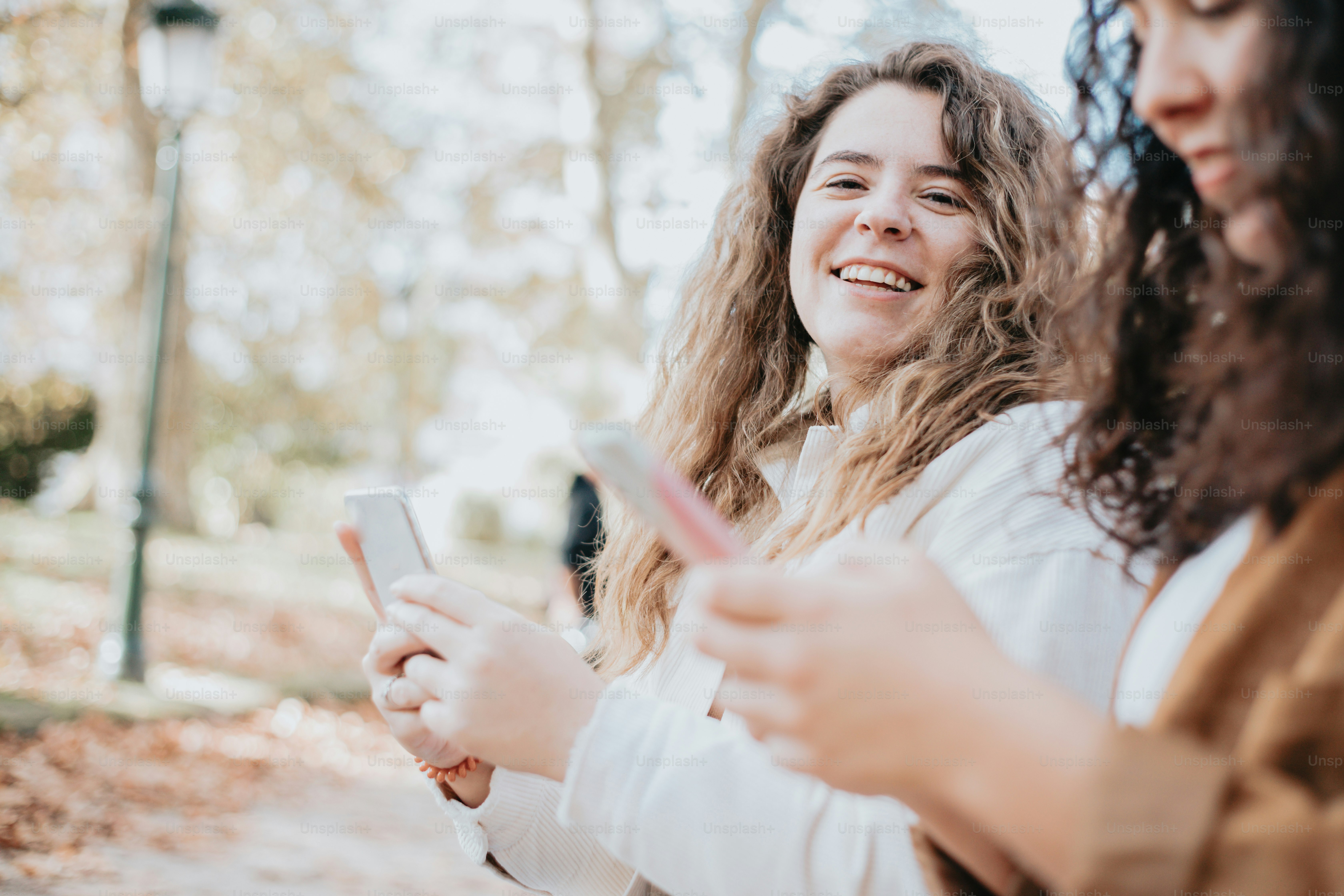 two women standing next to each other looking at their cell phones