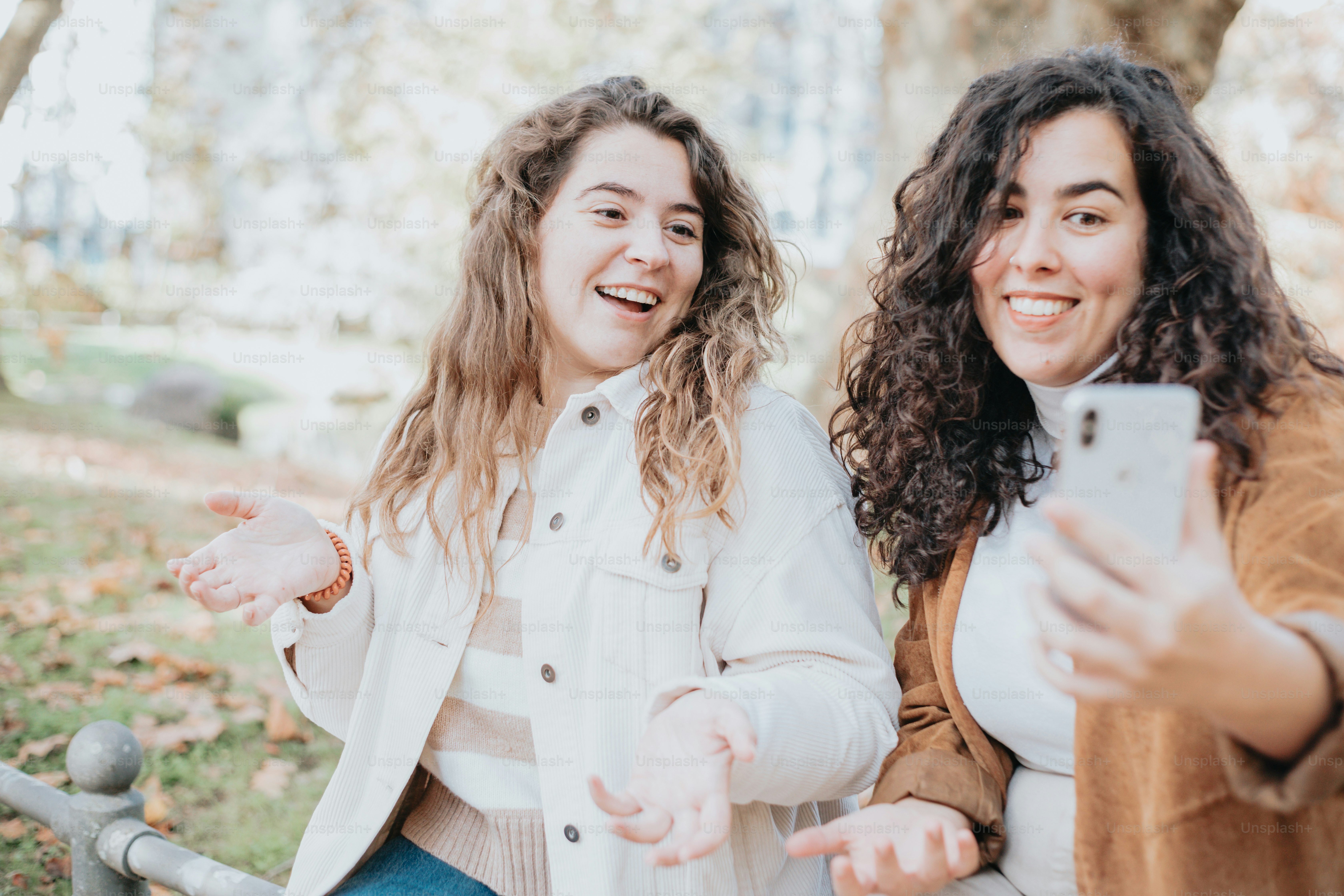 Zwei Frauen sitzen auf einer Bank und eine hält ein Handy in der Hand