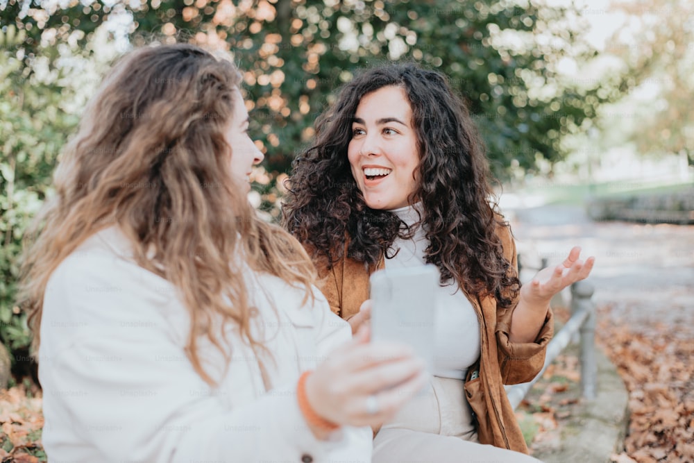 two women sitting on a bench talking to each other