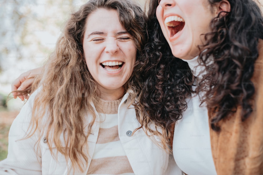 two women laugh and laugh together in a park