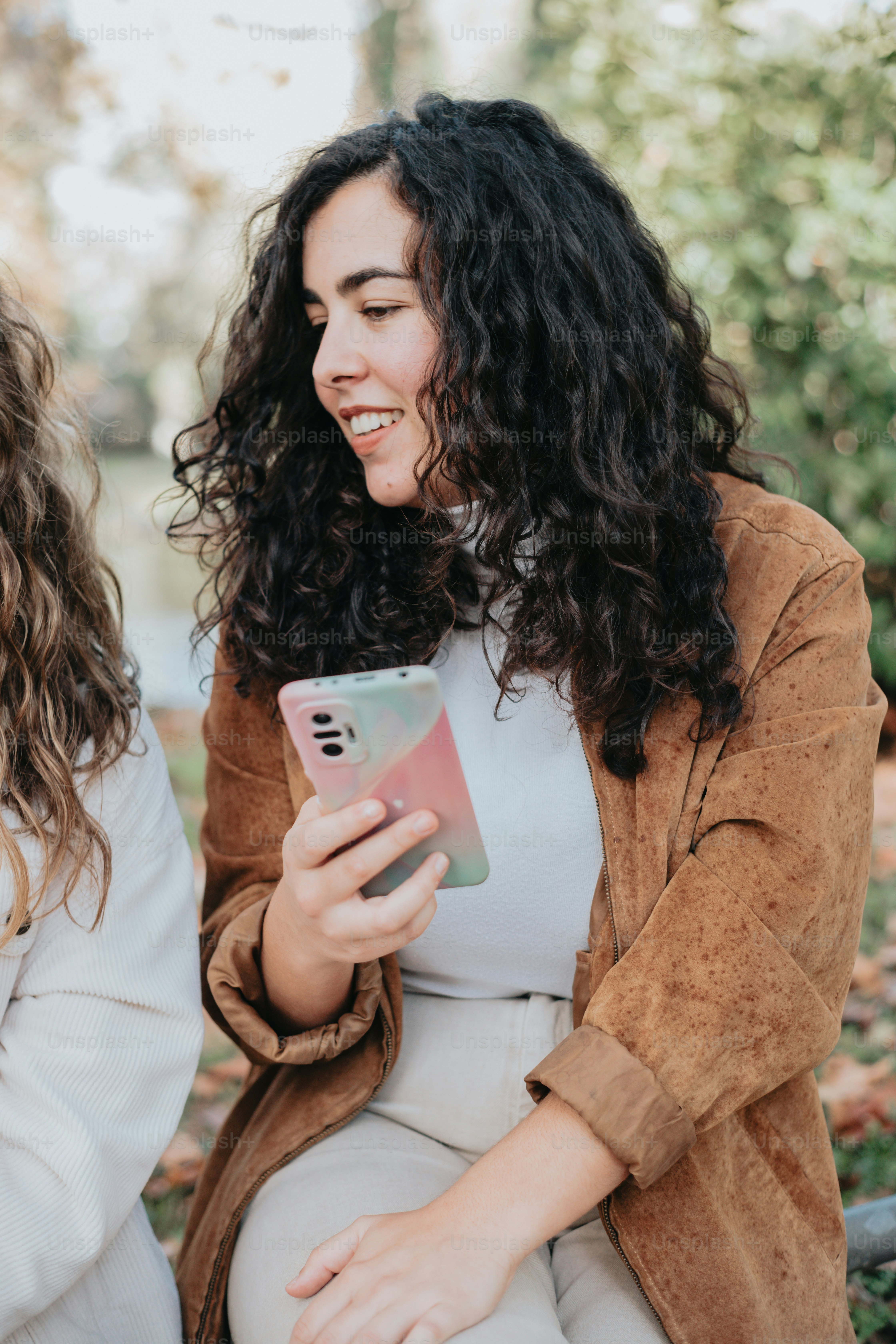 Zwei Frauen, die nebeneinander sitzen und auf ein Handy schauen