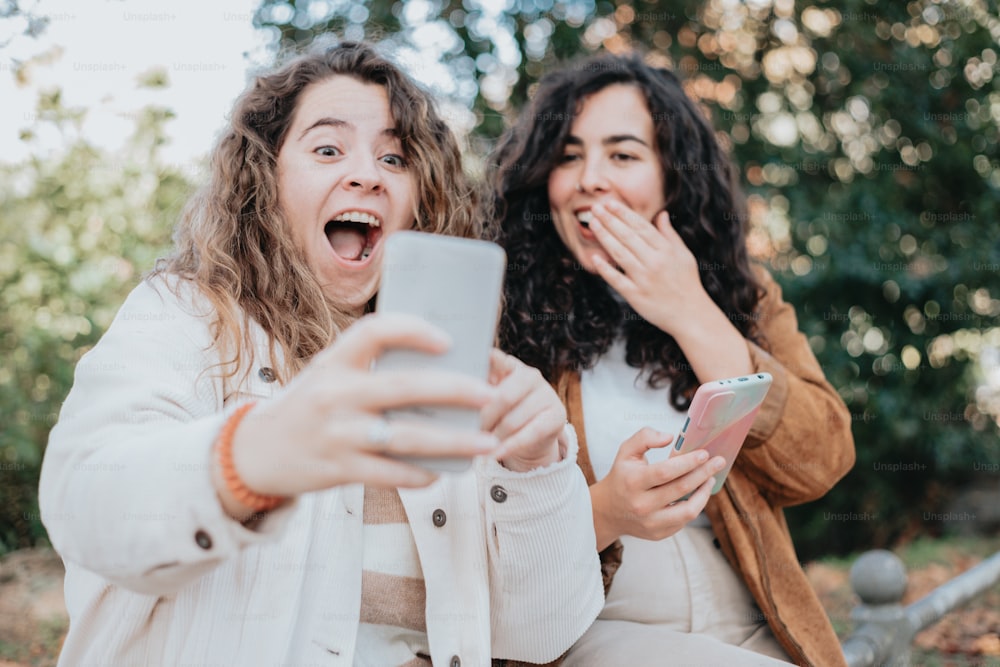 two women are laughing while looking at a cell phone