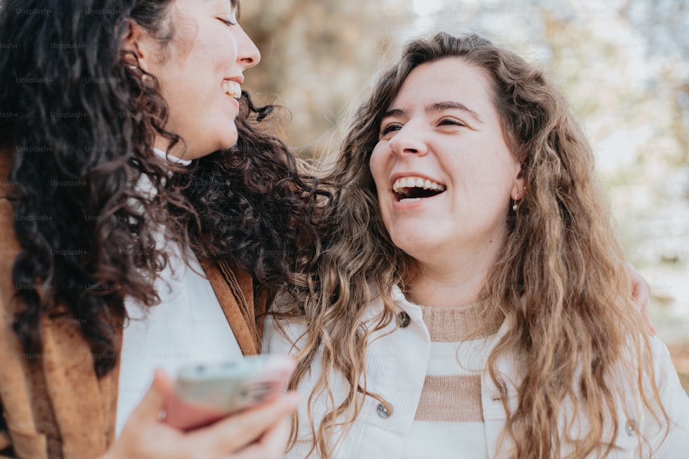 Due donne che ridono e tengono in mano un telefono cellulare