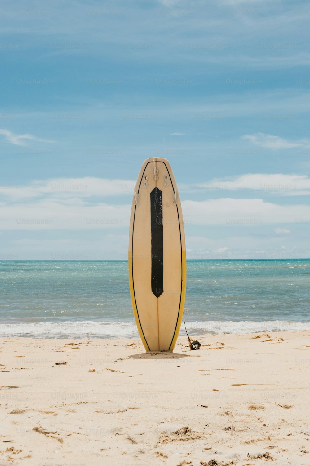 ein Surfbrett, das auf einem Sandstrand sitzt