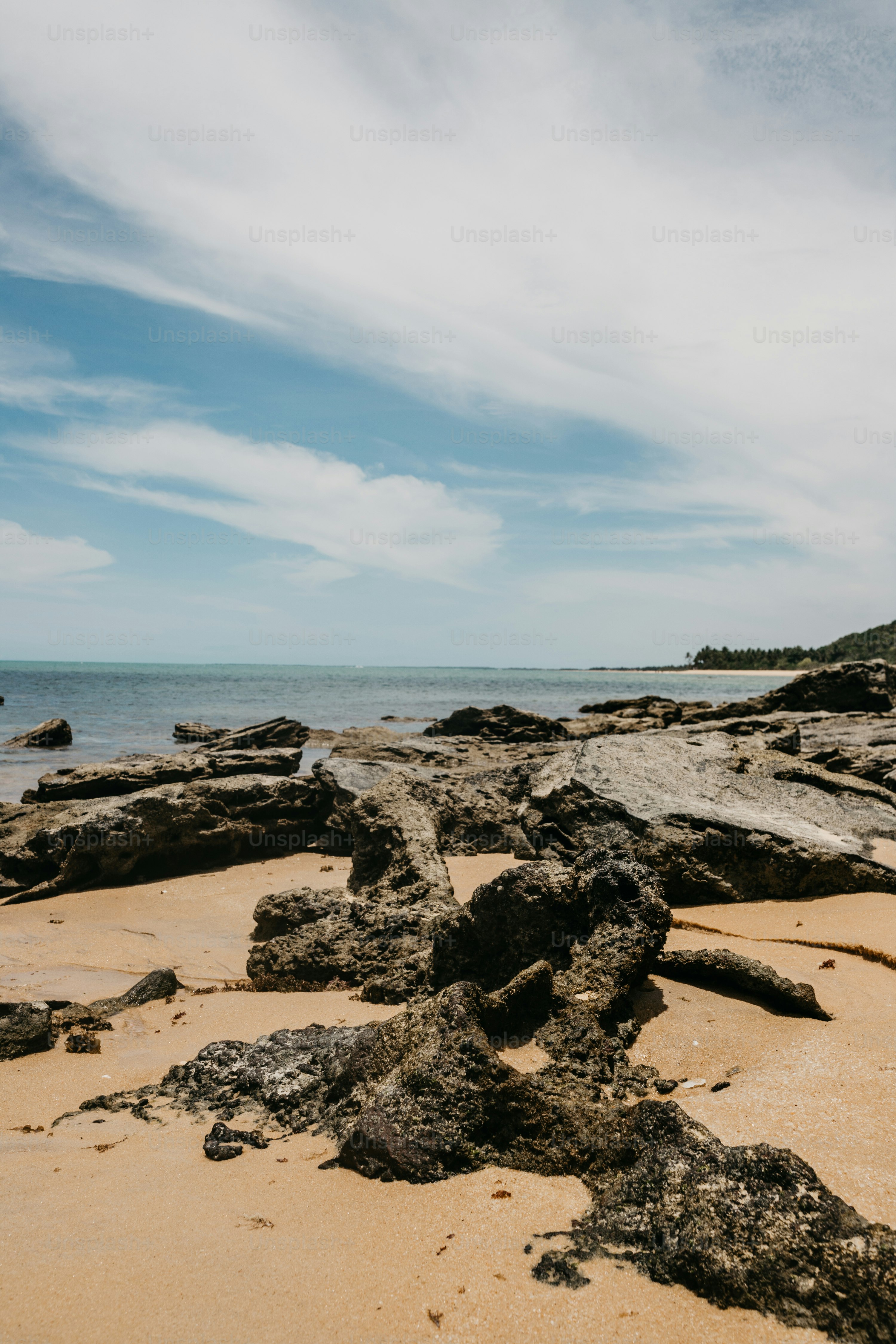 A beach with rocks and water under a cloudy sky photo – Shoreline Image ...