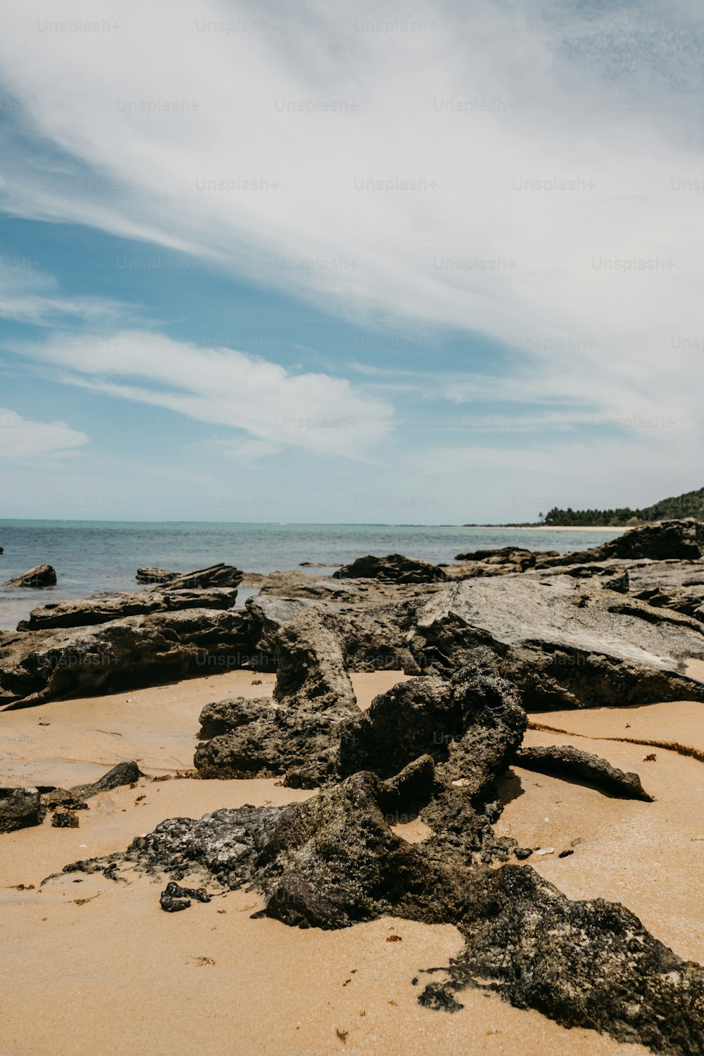Une plage avec des rochers et de l’eau sous un ciel nuageux
