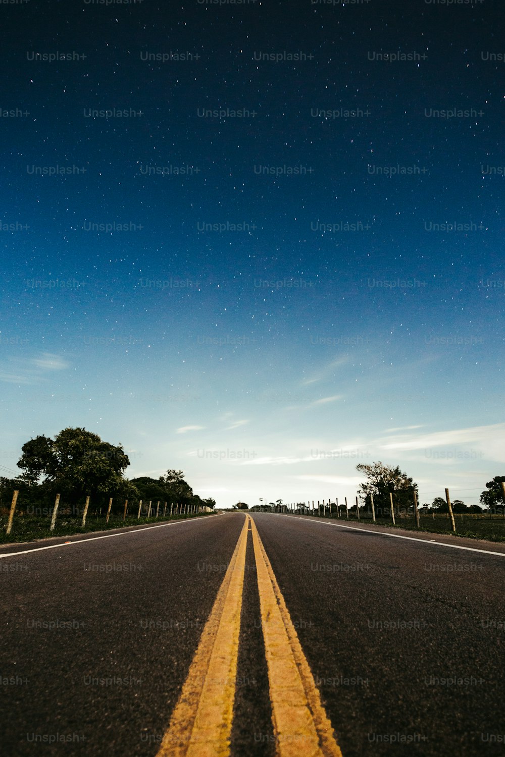 an empty road with a sky full of stars