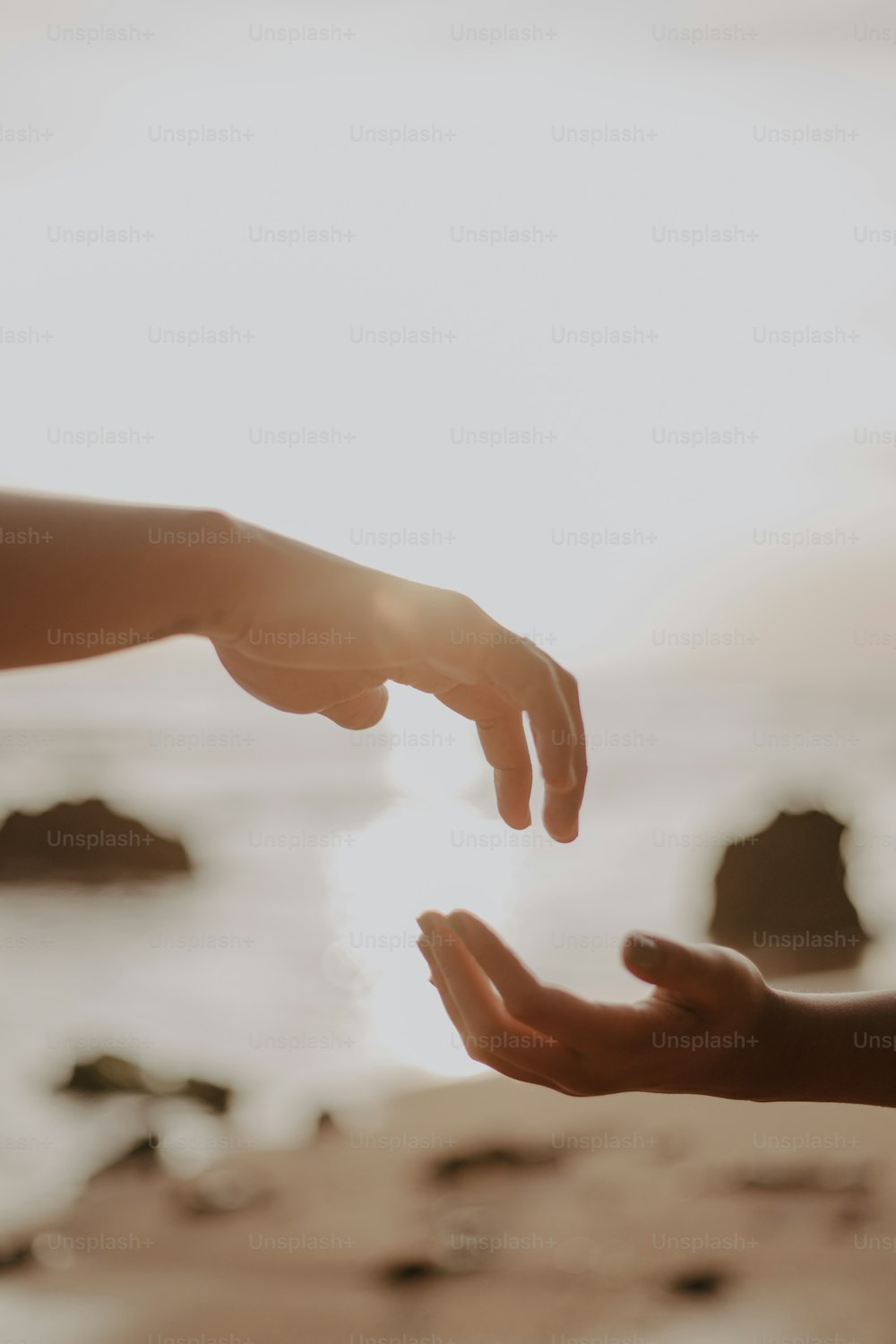 two people reaching out towards each other on a beach