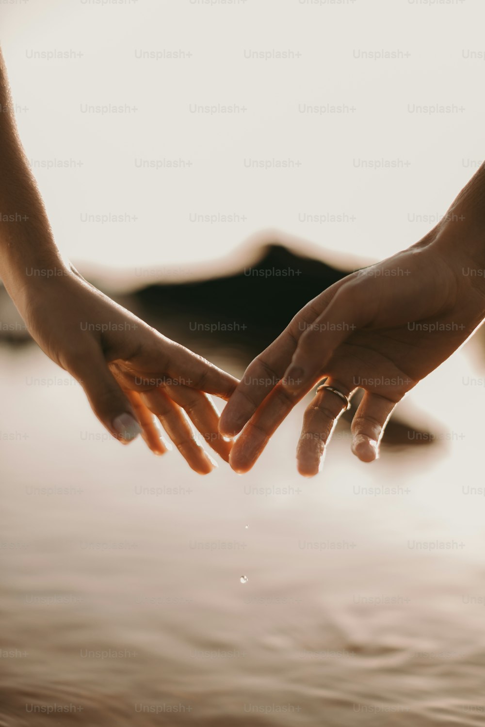 two people holding hands over a body of water