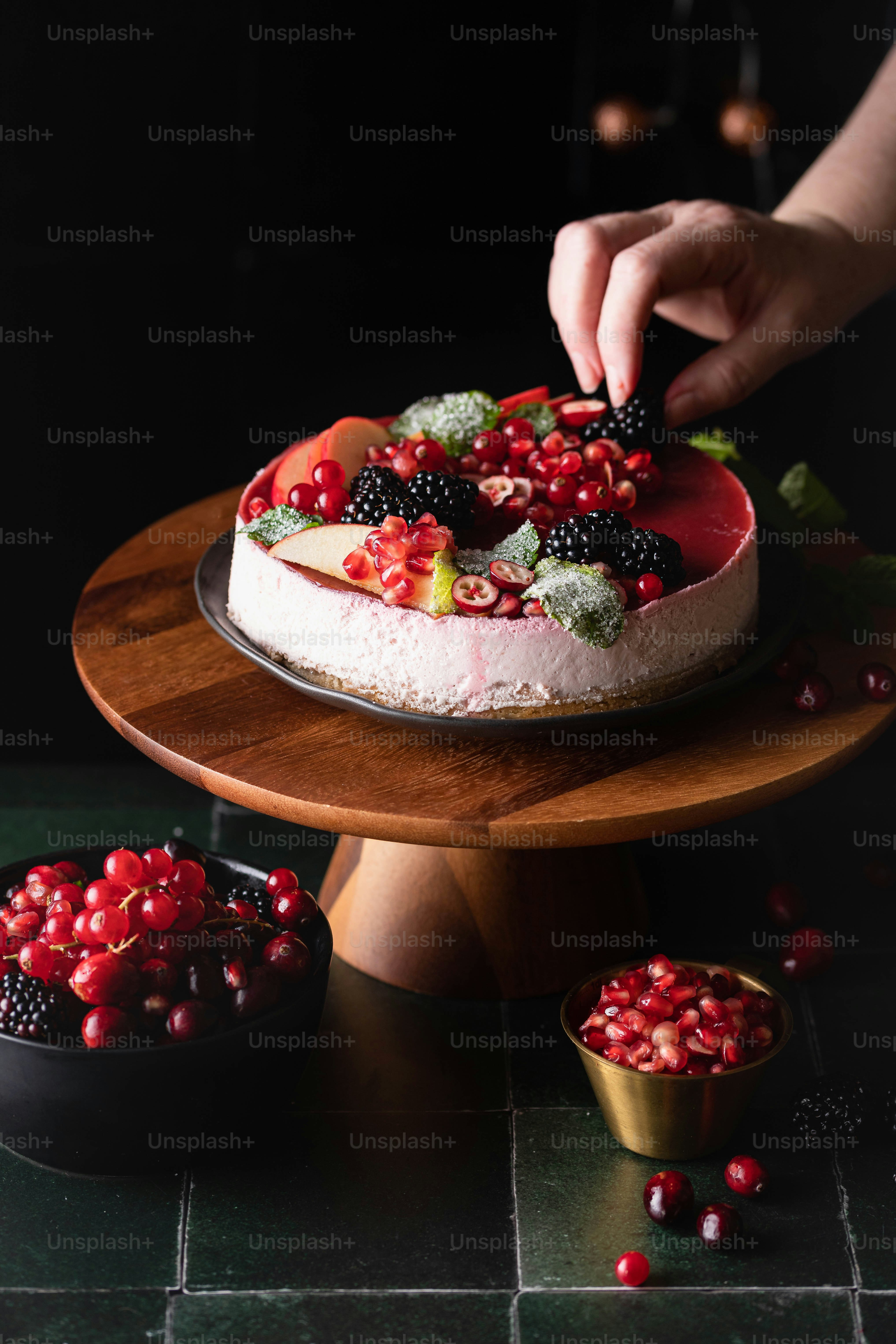 Eine Person dekoriert einen Kuchen mit Beeren
