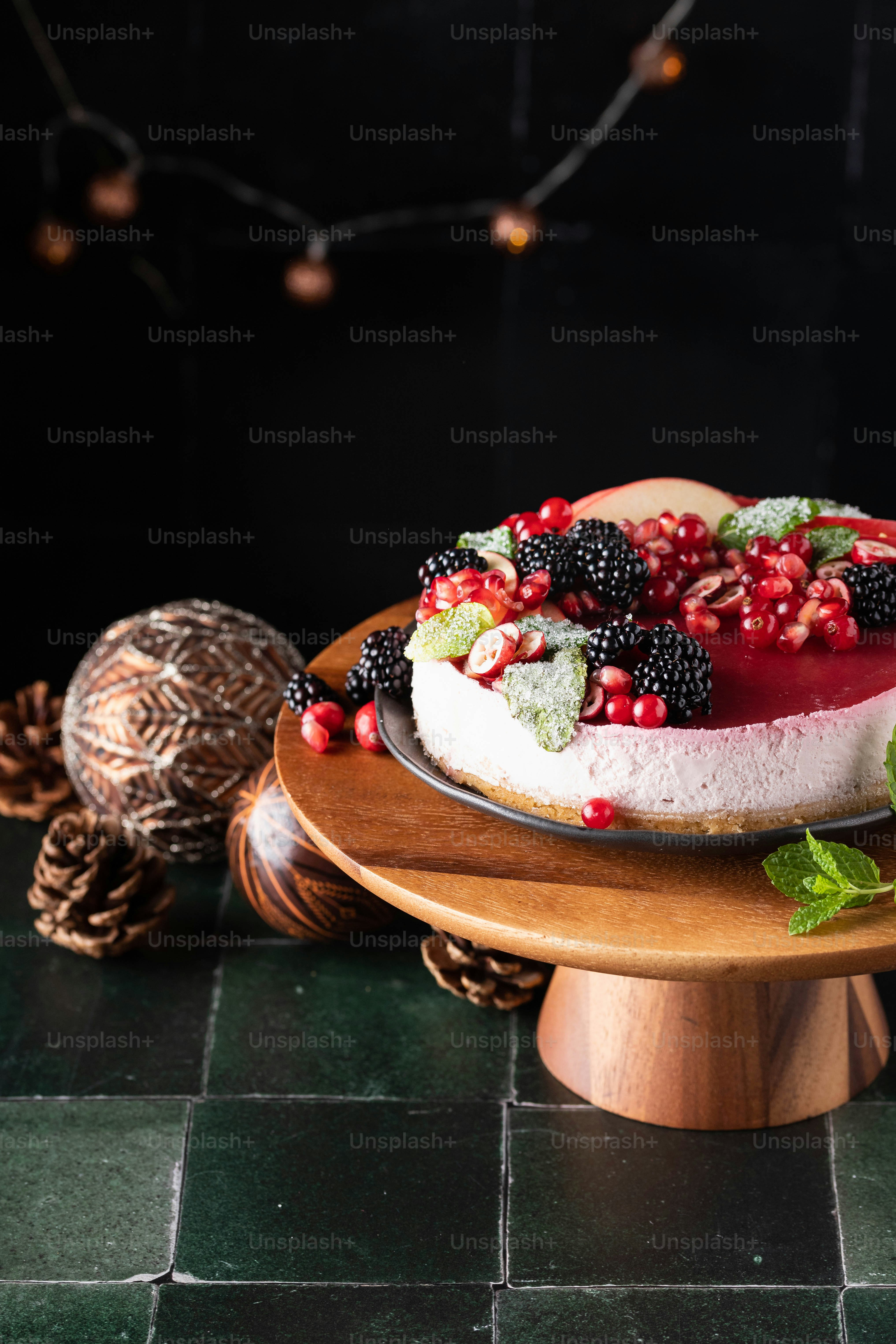 a cheesecake with berries and mint on a wooden plate