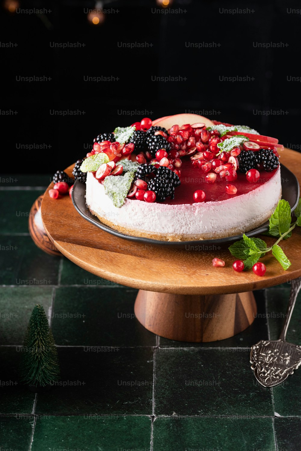 a cheesecake with berries and mint on a wooden plate