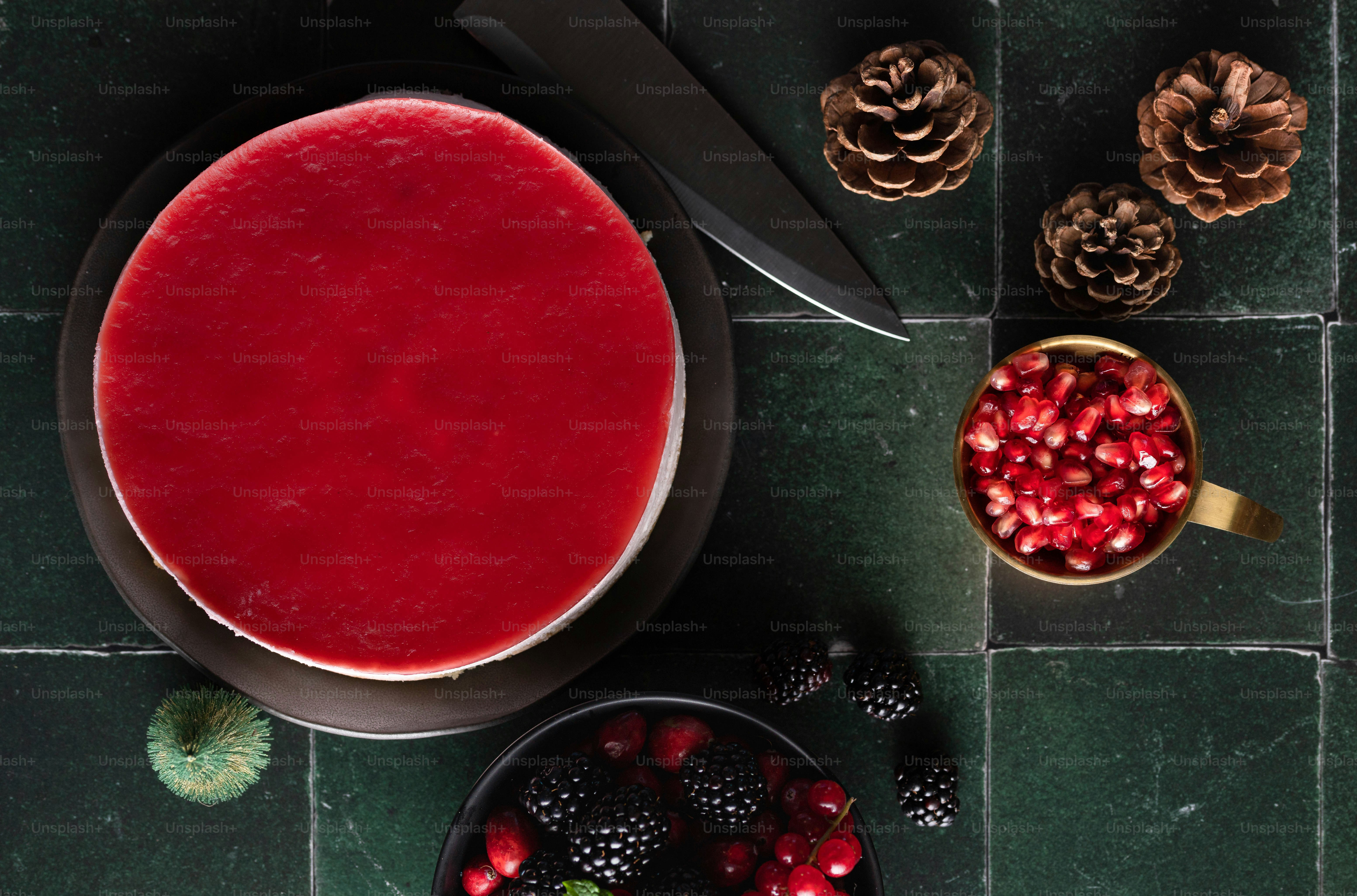 a bowl of raspberry sauce next to a bowl of berries and pine cones