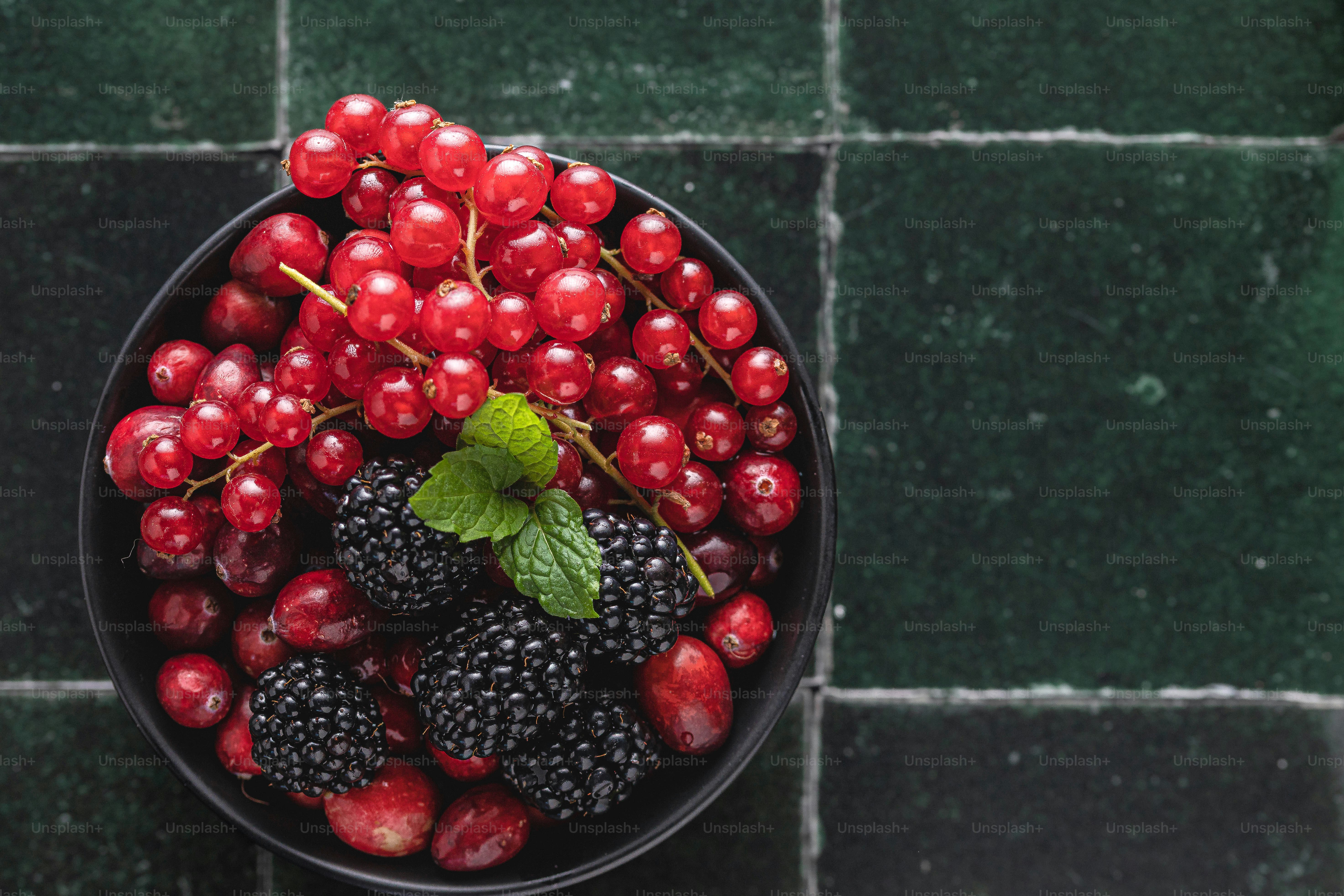 a bowl of berries and raspberries on a tiled floor