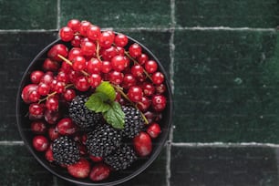 a bowl of berries and raspberries on a tiled floor