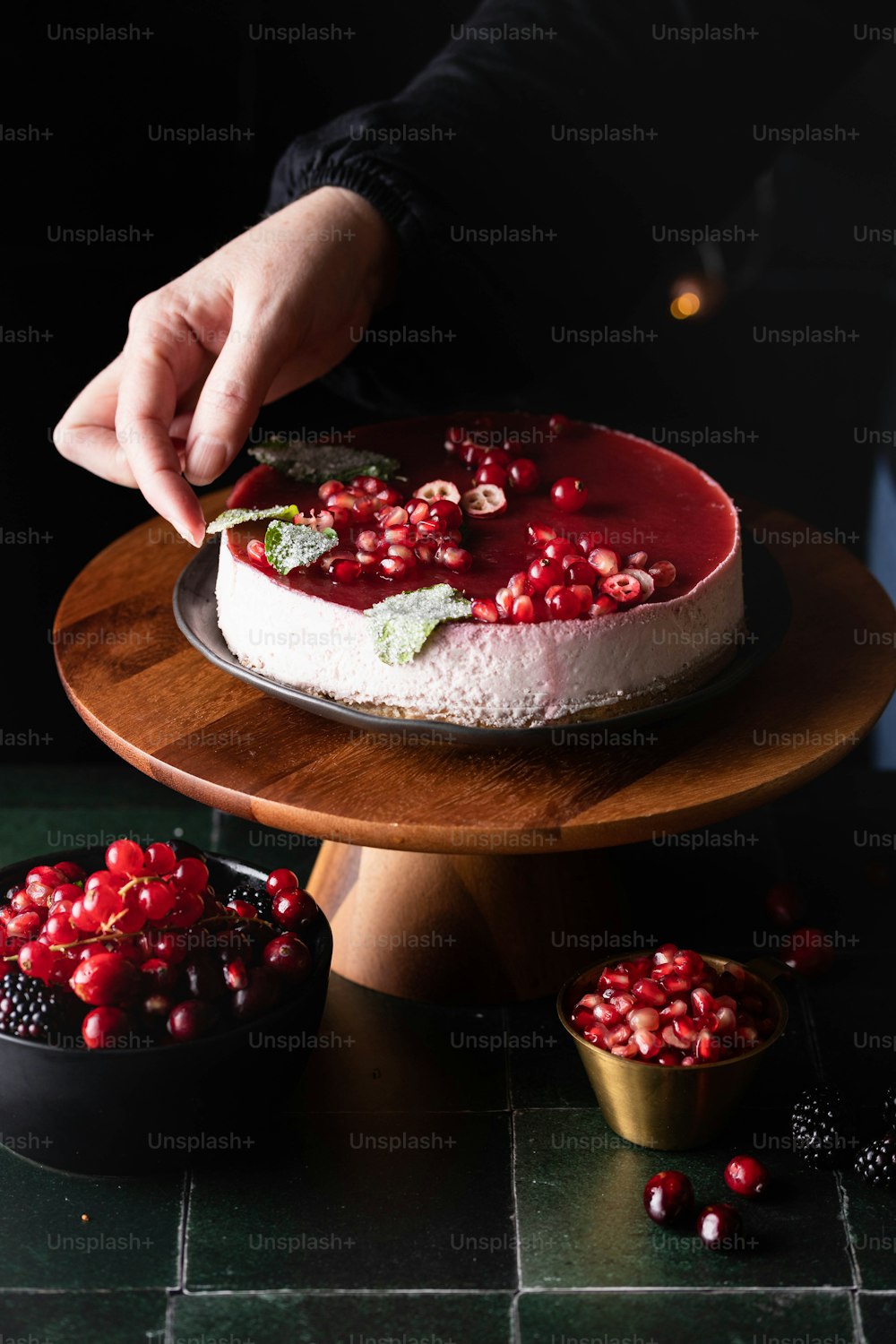 a person decorating a cake with pomegranates