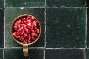 a bowl of pomegranate on a green tiled floor