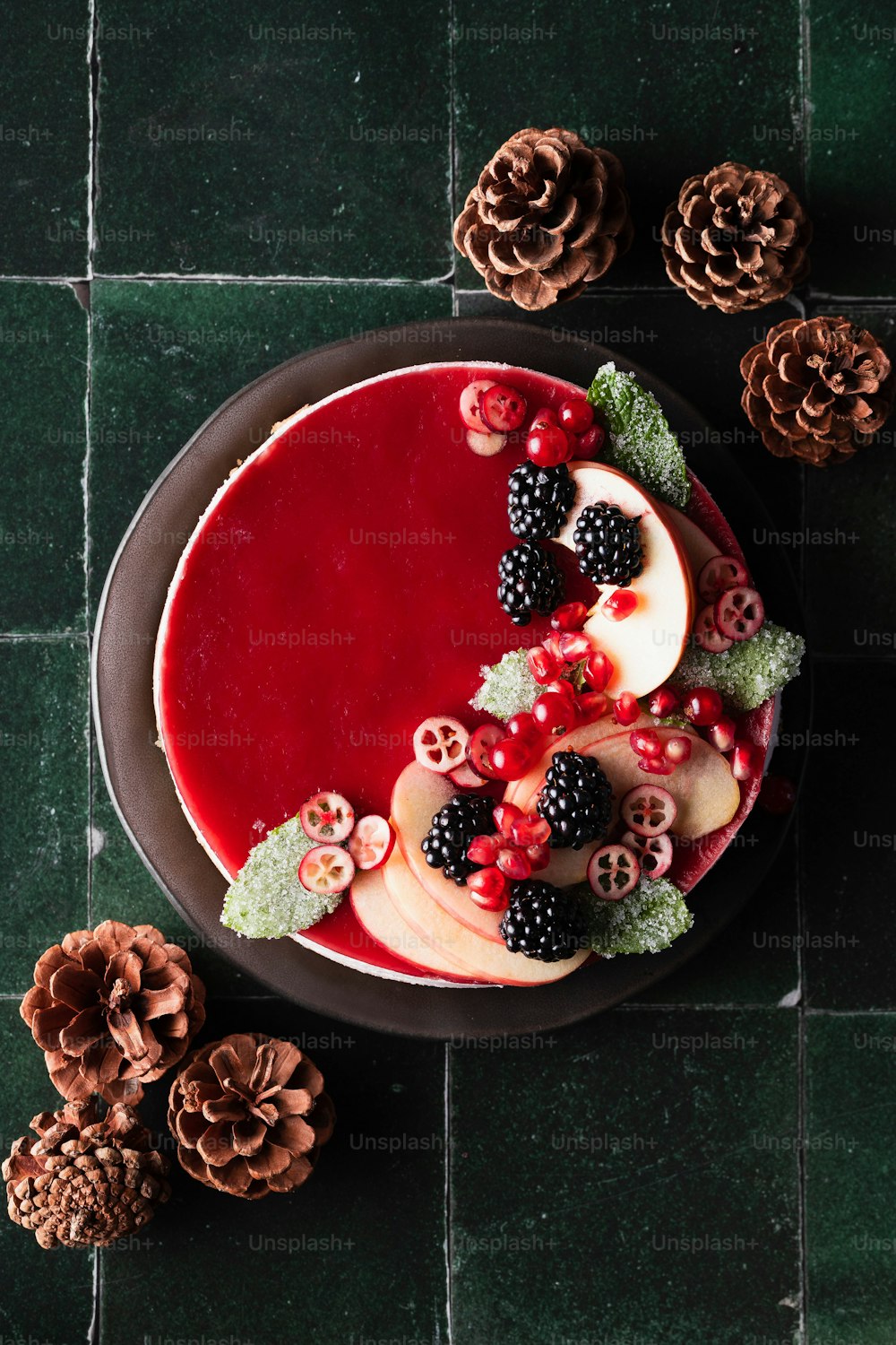 a cake with berries and pine cones on a table