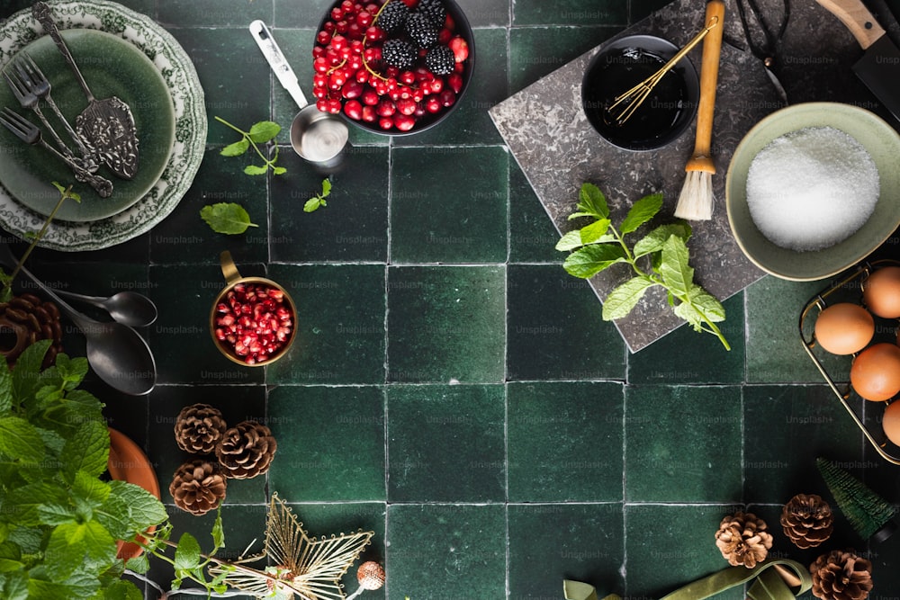 um piso de azulejos verdes coberto com tigelas de frutas e legumes