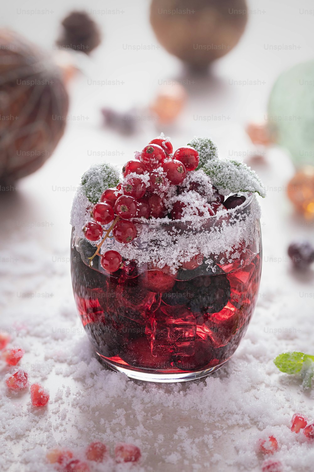 a small glass bowl filled with berries on top of snow