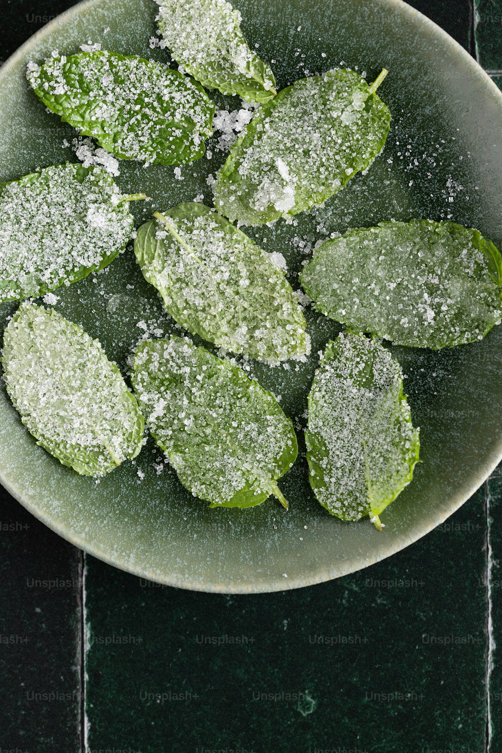 a bowl filled with green leaves covered in powdered sugar