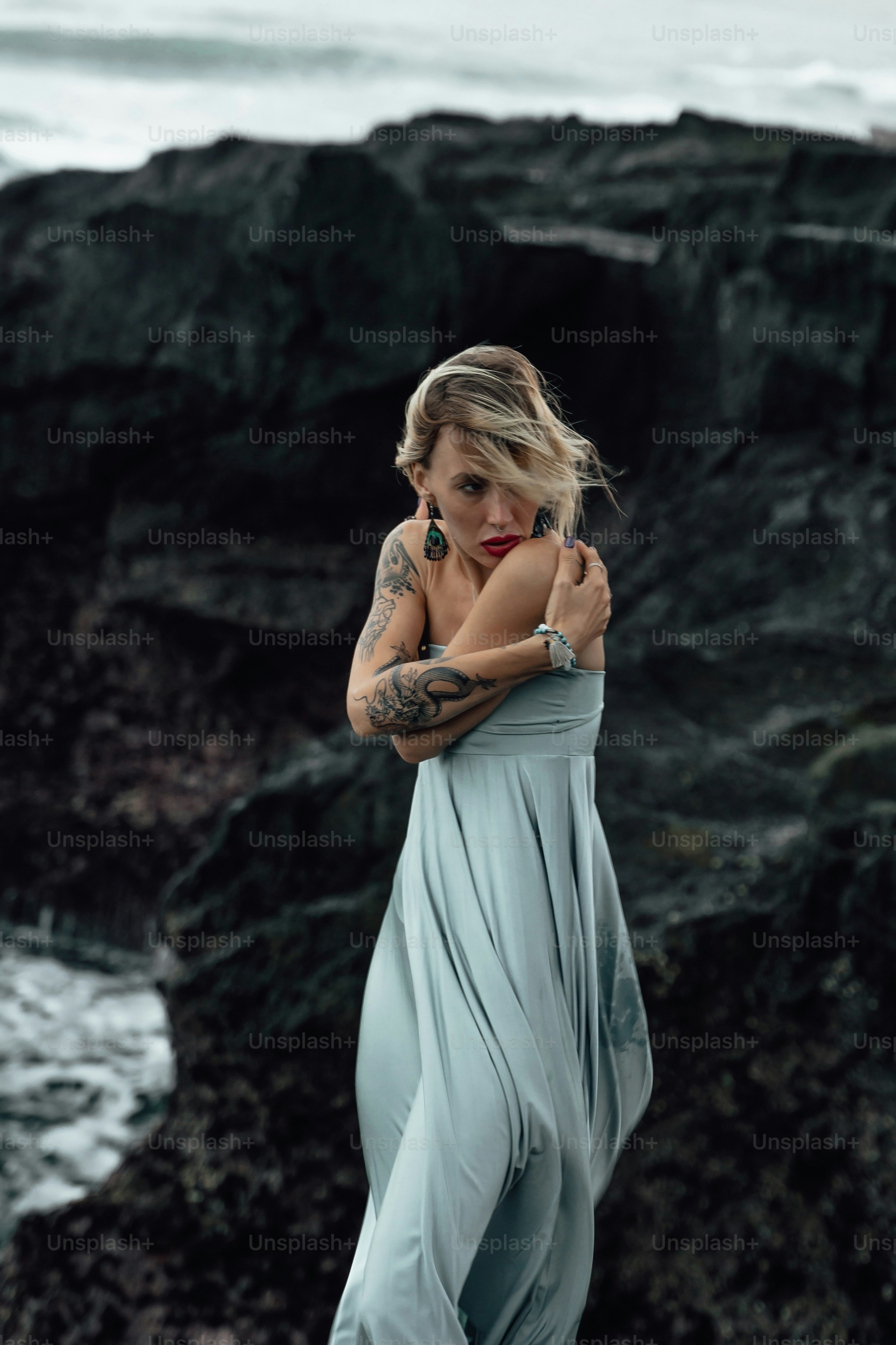 a woman in a long dress standing by the ocean