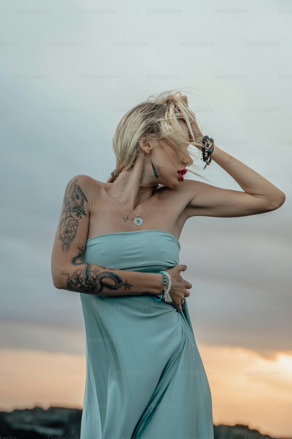 a woman in a blue dress with a tattoo on her arm