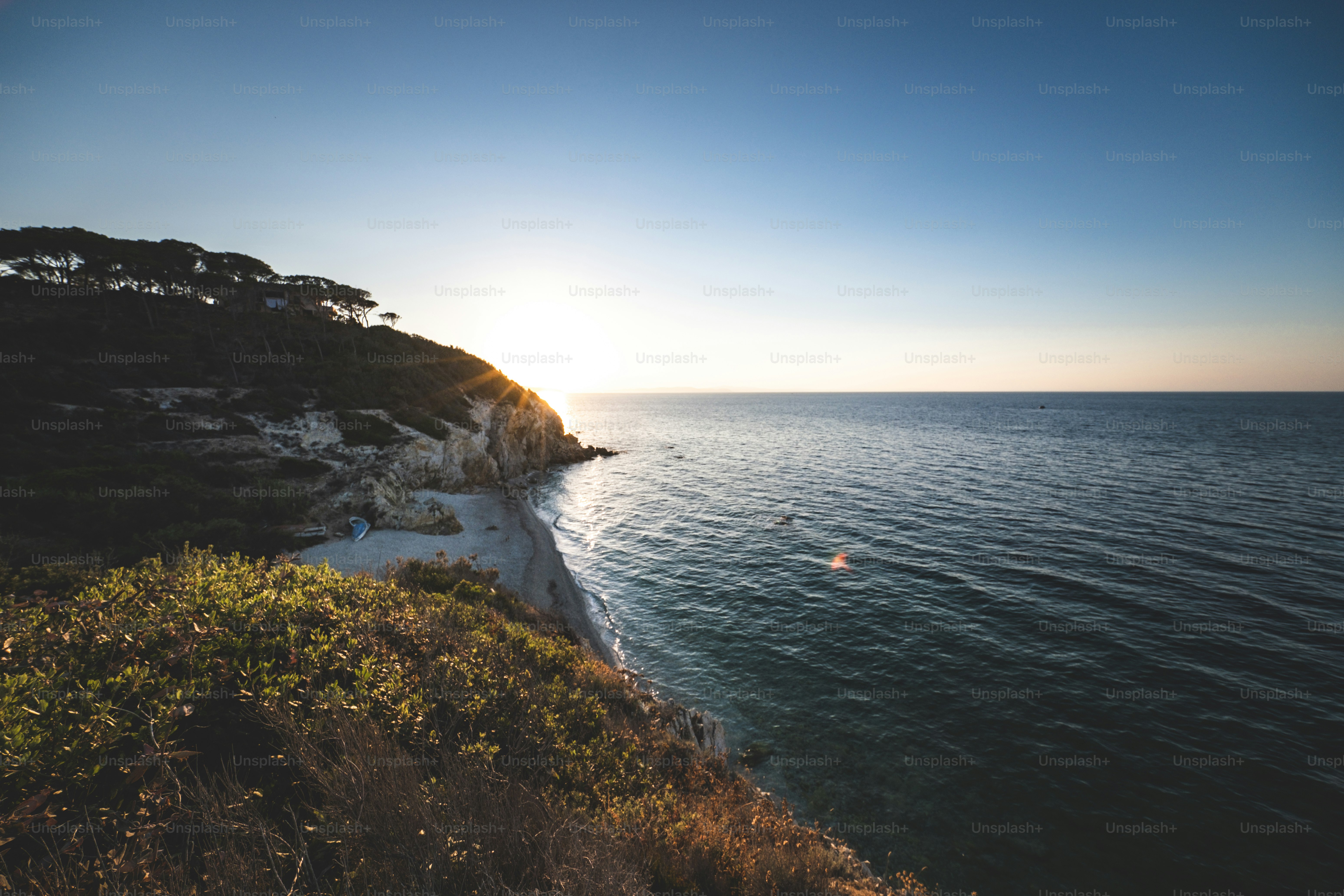 the sun is setting over the water near the shore