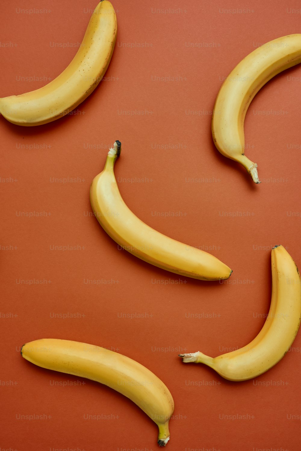 Un grupo de tres plátanos sentados encima de una mesa roja